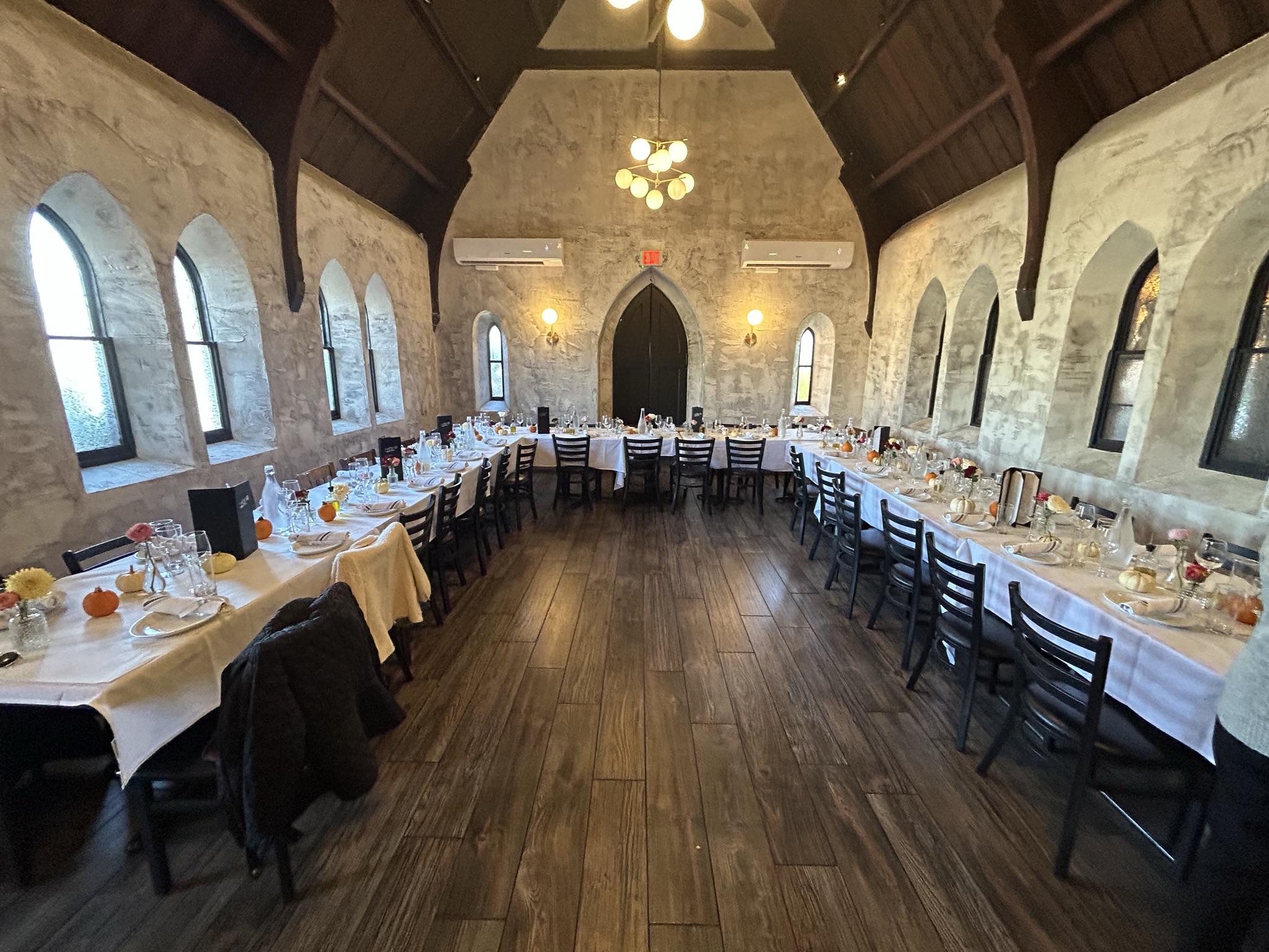 The Church Room set with long banquet tables beneath the original arched windows