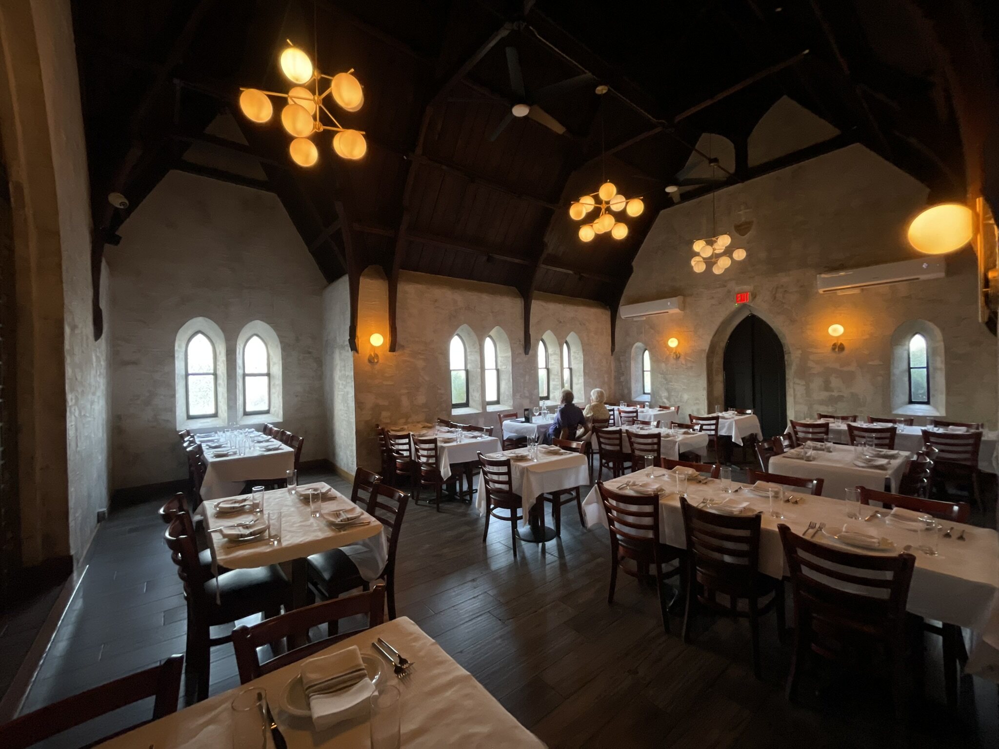 The Church Room \u2014 the 1850 nave, with white-linen tables beneath a vaulted timber ceiling and Gothic arched windows